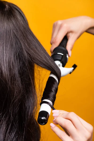 Vista cortada de cabeleireiro usando ferro de ondulação isolado no amarelo — Fotografia de Stock