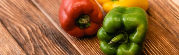 Colorful ripe bell peppers on wooden table, panoramic shot — Stock Photo