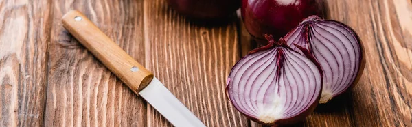 Cut red onion near knife on wooden table, panoramic shot — Stock Photo