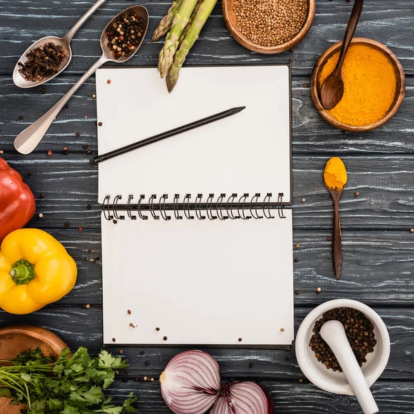 Vista superior de verduras frescas de colores y especias cerca de cuaderno en blanco en la superficie de madera — Stock Photo