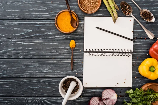 Vista superior de vegetais coloridos frescos e especiarias perto de notebook em branco na superfície de madeira — Fotografia de Stock