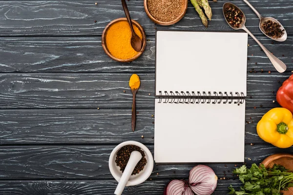 Draufsicht auf frisches, buntes Gemüse und Gewürze in der Nähe von blankem Notizbuch auf Holzoberfläche — Stockfoto
