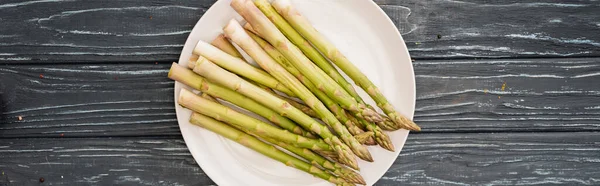 Vista dall'alto di asparagi freschi su piatto su superficie di legno, colpo panoramico — Foto stock