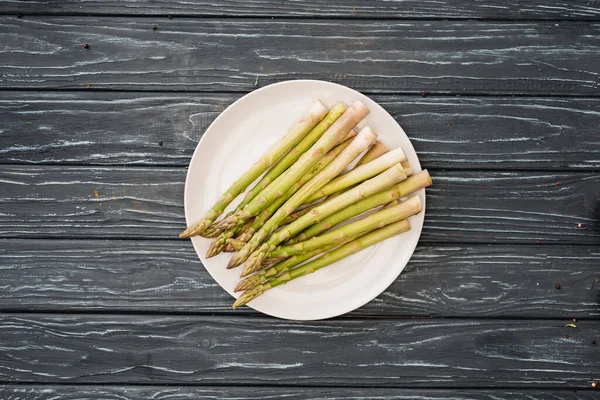 Ansicht von frischem Spargel auf Teller auf Holzoberfläche — Stockfoto