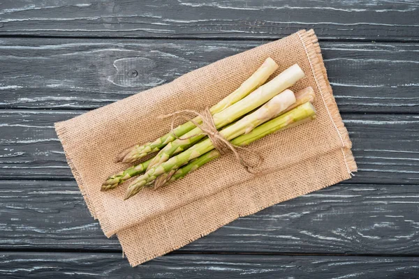 Top view of fresh asparagus on burlap on wooden surface — Stock Photo