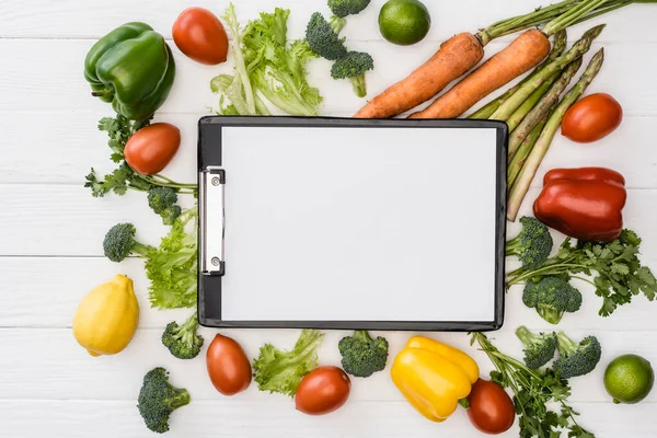 Top view of fresh ripe vegetables and fruits near empty clipboard on wooden white background — Stock Photo