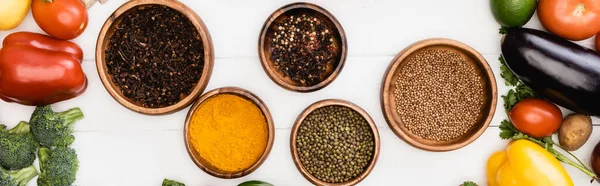 Top view of fresh ripe vegetables around bowls with spices on wooden white background, panoramic shot — Stock Photo