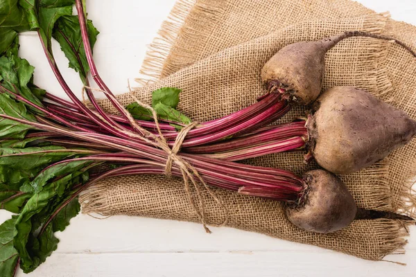 Top view of beetroot tied with rope on sackcloth on white wooden table — Stock Photo