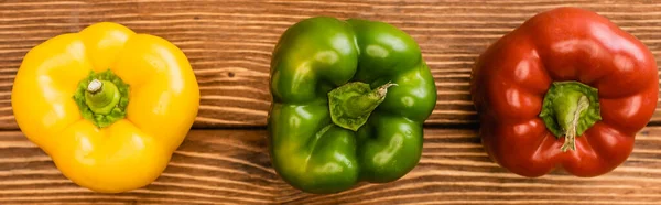 Top view of colorful ripe bell peppers on wooden table, panoramic shot — Stock Photo