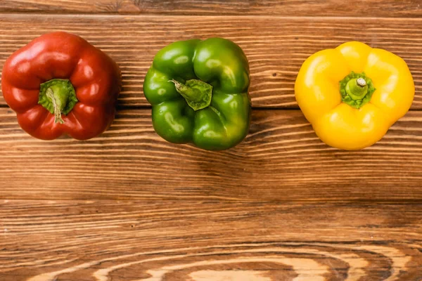 Top view of colorful ripe bell peppers on wooden table — Stock Photo