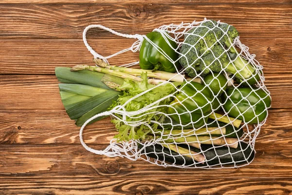 Vue du dessus des légumes verts frais mûrs dans un sac à ficelle sur une table en bois — Photo de stock