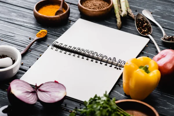 Foco seletivo de vegetais coloridos frescos e especiarias perto de notebook em branco na superfície de madeira — Fotografia de Stock