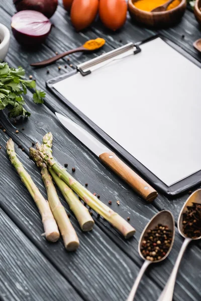 Messa a fuoco selettiva degli appunti in bianco vicino a coltello e verdure sulla superficie di legno — Foto stock