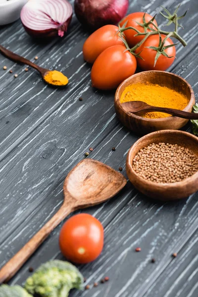 Enfoque selectivo de verduras frescas maduras y especias sobre fondo de madera - foto de stock