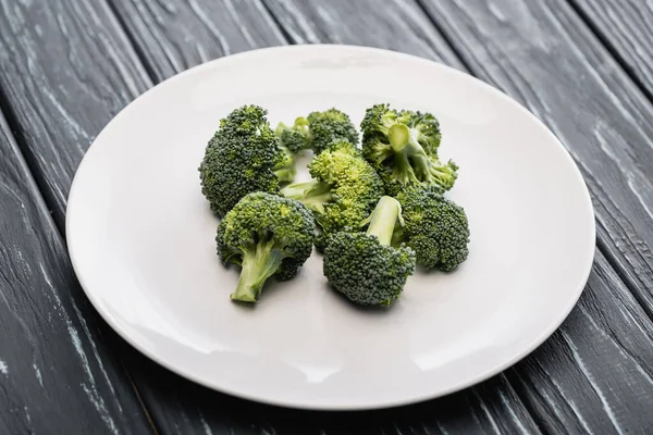 Brócoli verde fresco en plato blanco sobre superficie de madera - foto de stock