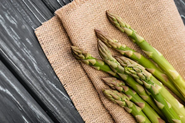 Close up view of fresh green asparagus on burlap on wooden surface — Stock Photo