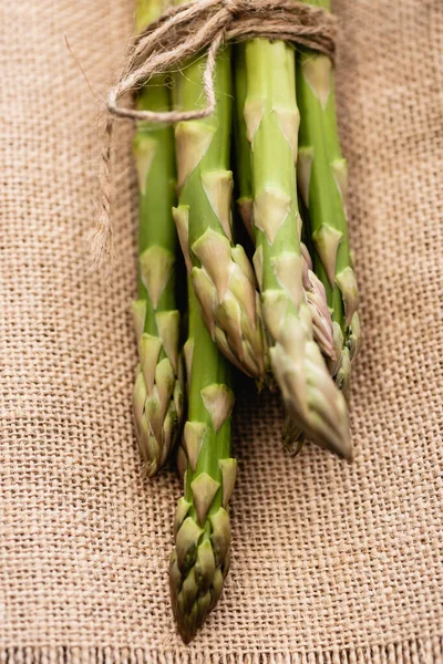 Bundle of fresh green asparagus on burlap — Stock Photo