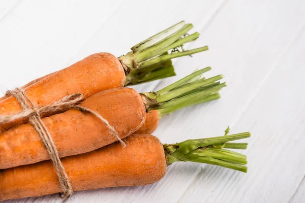 Nahaufnahme von frischen Möhren mit Seil auf weißem Holztisch — Stockfoto