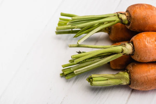 Vue rapprochée des carottes fraîches attachées à la corde sur une table en bois blanc — Photo de stock