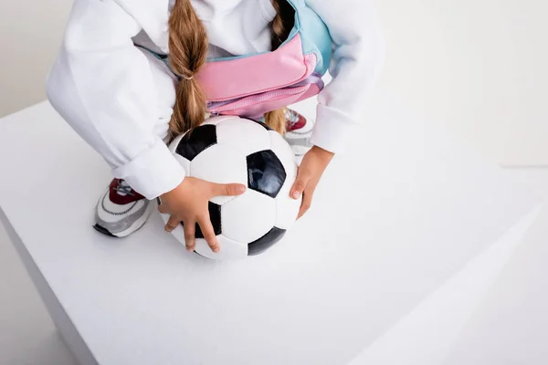 Recortado vista de chica en ropa deportiva posando con pelota de fútbol en cubo - foto de stock