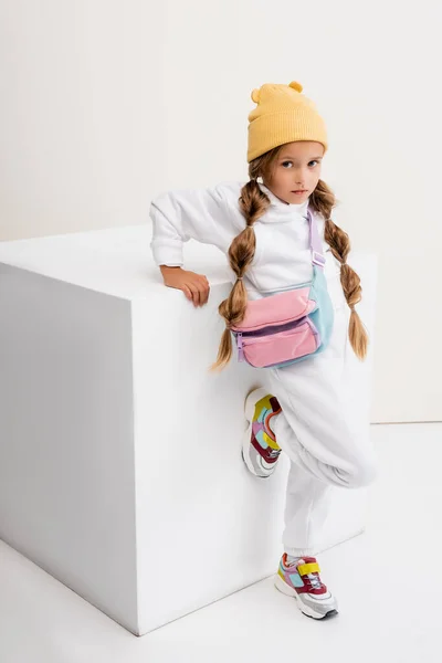 Menina loira em sportswear posando perto de cubo no fundo branco — Fotografia de Stock