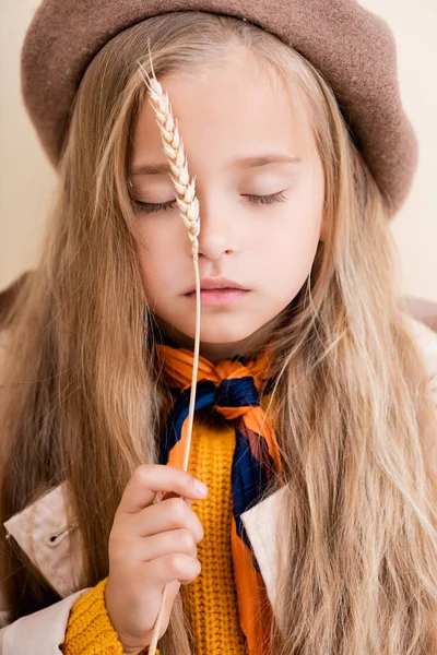 Fashionable blonde girl with closed eyes in autumn outfit holding wheat spike — Stock Photo