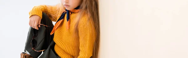 Cropped view of fashionable blonde girl in autumn outfit with sunglasses on beige and white background, panoramic shot — Stock Photo