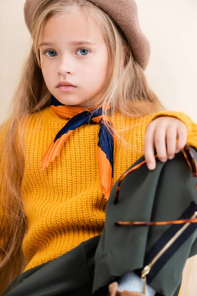 Fashionable blonde girl in autumn outfit and sunglasses isolated on beige — Stock Photo