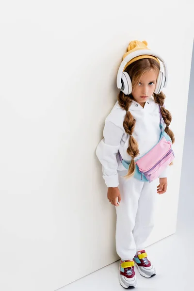 Menina loira em sportswear e fones de ouvido posando no fundo branco — Fotografia de Stock