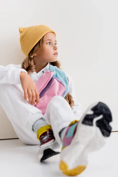 Selective focus of blonde girl in sportswear sitting near white wall — Stock Photo