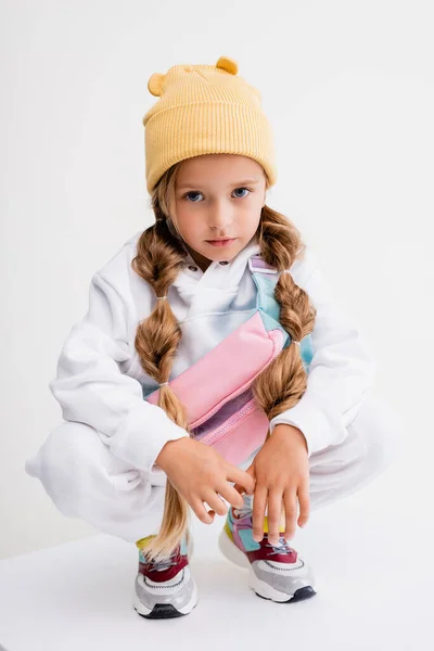 Menina loira em sportswear sentado no cubo isolado no branco — Fotografia de Stock