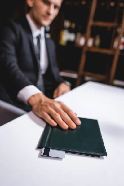 Enfoque selectivo del hombre de traje poniendo la factura del restaurante con tarjeta de crédito en la mesa - foto de stock