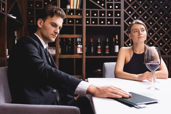 Focus selettivo dell'uomo mettendo conto ristorante con carta di credito sul tavolo vicino fidanzata con bicchiere di vino — Foto stock