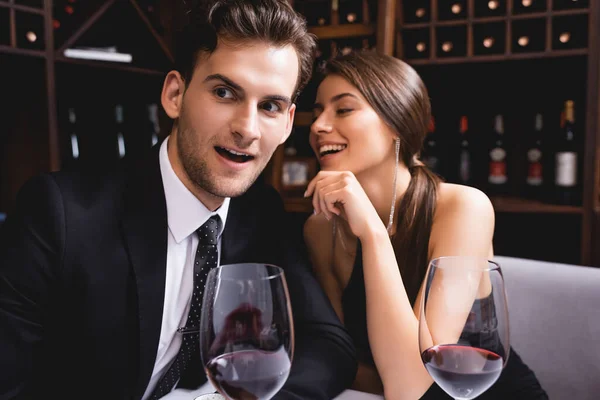 Selective focus of man in suit sitting near glasses of wine and elegant girlfriend in restaurant — Stock Photo