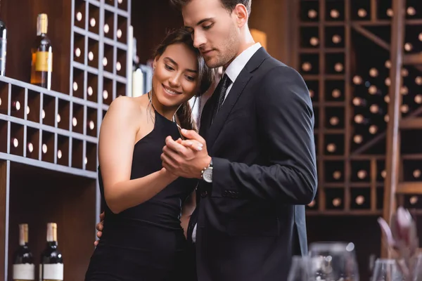 Selective focus of young man in suit dancing with elegant girlfriend in restaurant — Stock Photo