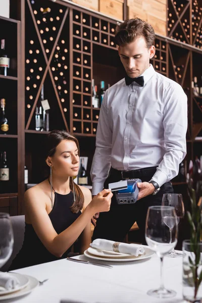 Selektiver Fokus der eleganten Frau, die mit Kreditkarte beim Kellner im Restaurant bezahlt — Stockfoto