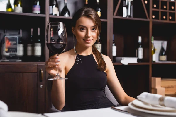 Selective focus of young woman with glass of wine sitting at table in restaurant — Stock Photo