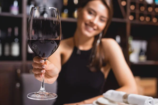 Enfoque selectivo de la mujer mostrando copa de vino en el restaurante - foto de stock