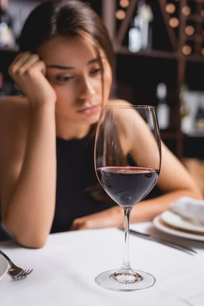 Focus selettivo di vetro di vino vicino a donna sconvolta in ristorante — Foto stock