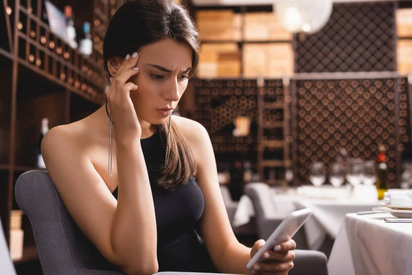 Focus selettivo della donna pensosa che utilizza lo smartphone nel ristorante — Foto stock