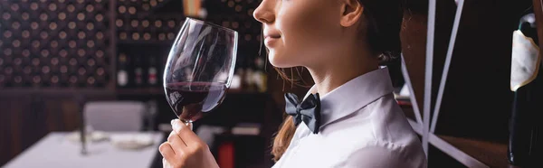 Panoramic shot of sommelier holding glass of wine in restaurant — Stock Photo
