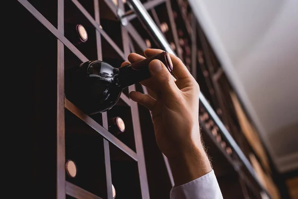 Ausgeschnittene Ansicht eines Sommeliers, der eine Flasche Wein nimmt, während er im Restaurant arbeitet — Stockfoto