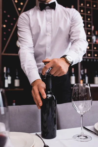 Ausgeschnittene Ansicht eines Sommeliers, der eine Flasche Wein mit Korkenzieher im Restaurant öffnet — Stockfoto