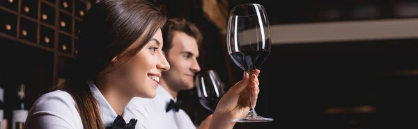 Orientation panoramique du sommelier regardant un verre de vin près d'un collègue au restaurant — Photo de stock