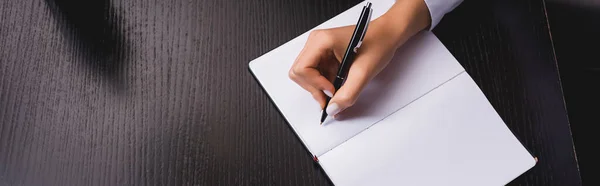 Horizontal image of woman writing on notebook at table — Stock Photo