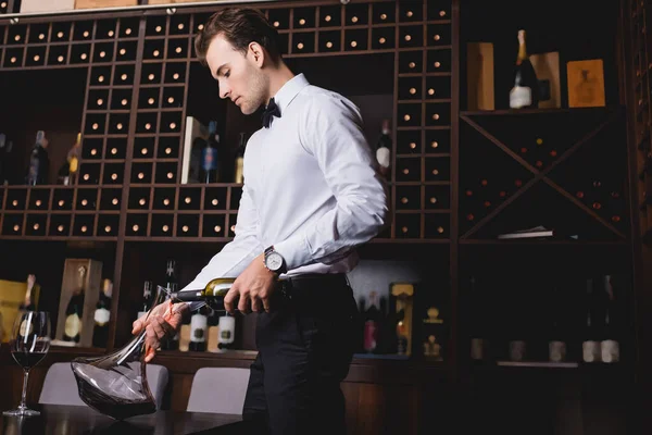 Sommelier in formal wear and bow tie pouring wine in decanter in restaurant — Stock Photo