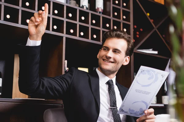 Selektiver Fokus eines Mannes im Anzug mit erhobener Hand, der im Restaurant wegschaut — Stockfoto