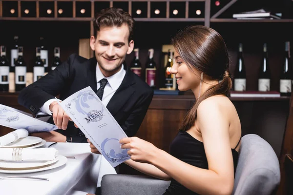 Selective focus of elegant couple looking at menu in restaurant — Stock Photo