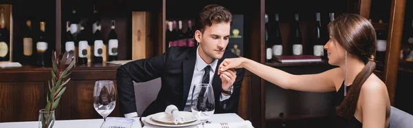 Panoramic shot of man in suit holding hand of girlfriend in restaurant — Stock Photo