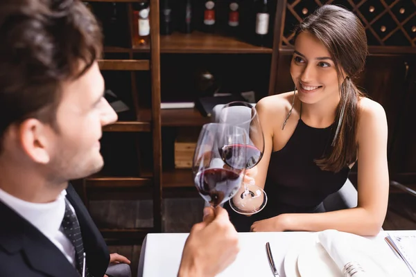 Selective focus of young couple clinking with wine in restaurant — Stock Photo